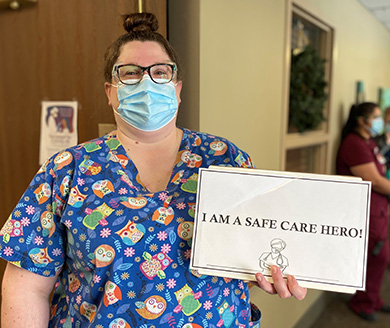 A Chaska staff member holding a sign at reads 'I am a safe care hero'
