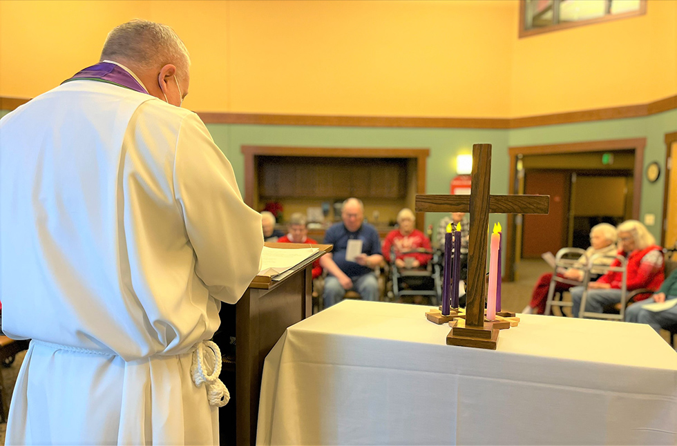 View of the inside of the chapel with Pastor Matty and a cross in the foreground.