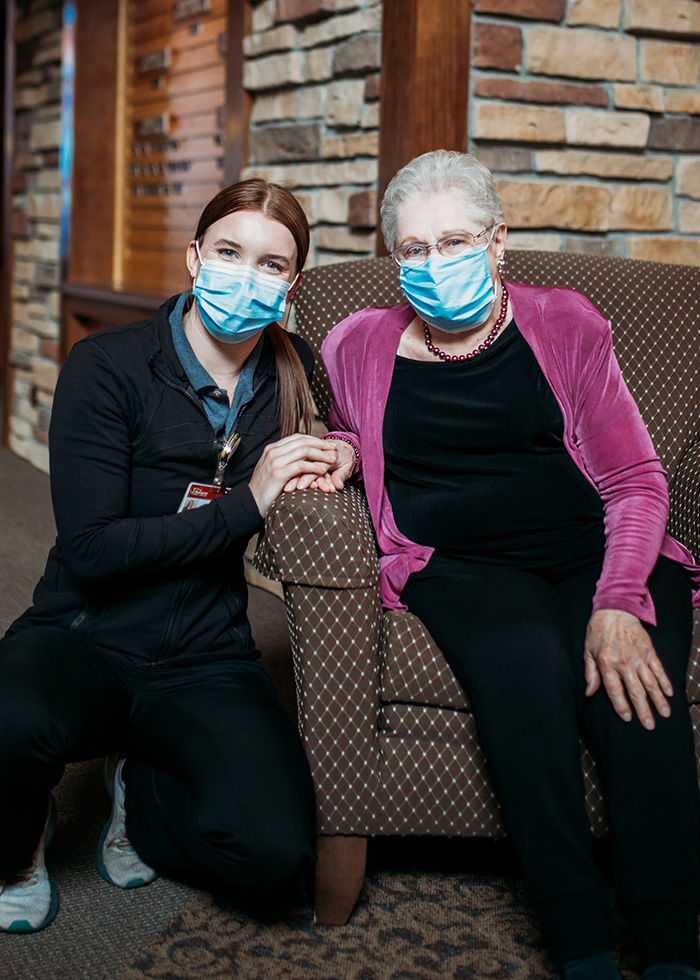 A nurse kneels next to a seated resident at Auburn Meadows Assisted Living in Waconia